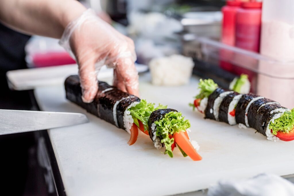 Chef hands cutting sushi roll at the litchen of the restaurant